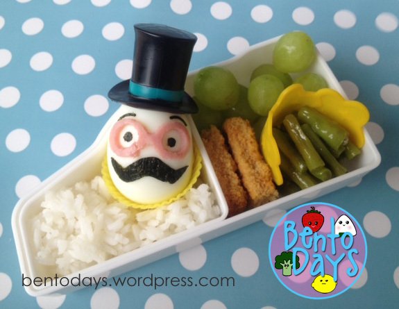 hard boiled eggs, wearing little top hats and mustaches cut out freehand using nori. Glasses cut out using ham.