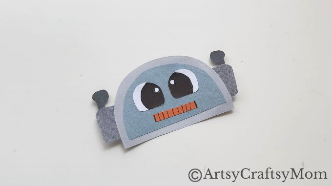 Attach the eyes and the mouth cutout on the head pattern of the robot figure.